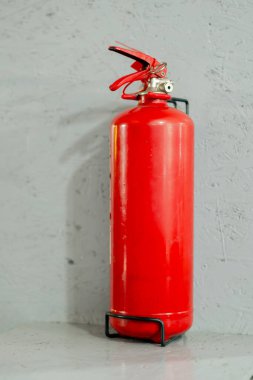 Gri bir duvardaki benzin istasyonunda kırmızı bir yangın söndürücü var.