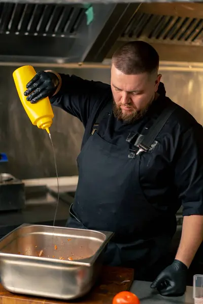 Professional Kitchen Chef Black Jacket Pours Oil Vegetables Iron Bowl — Stock Photo, Image