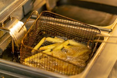 Profesyonel bir mutfakta yakın plan çekimde kızartma kızartmasını fritözde yağda kızartıyorum.