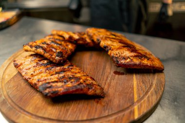 Profesyonel bir mutfakta, ahşap bir tabakta pişmiş pirzola var.