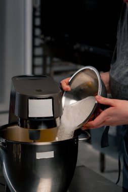 Profesyonel bir mutfakta el ele tutuşun. Demir bir masa üzerinde fırıncı makineye şeker dökün.