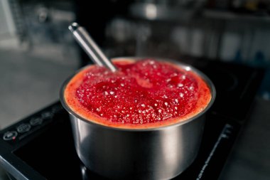Profesyonel mutfakta sobanın üstünde kiraz kaynatıyorlar.