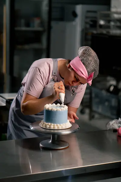 Profesyonel Bir Mutfakta Mavi Pastayı Kremayla Süsleyen Bir Kadın Fırıncının — Stok fotoğraf