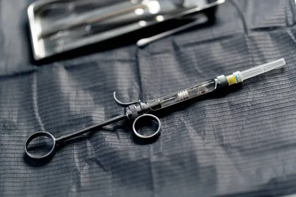 在牙科诊所里有一个用于麻醉病人的金属注射器在桌子上 — 图库照片