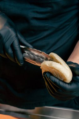 Bir şefin siyah eldiven giyip ekmeği açmadan önce maşa kullanırken ki fotoğrafı.