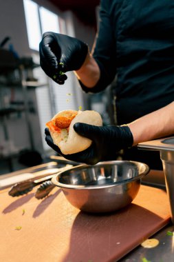 Siyah eldivenli şefi kapat. Farklı malzemeleri maşayla topuz yap.