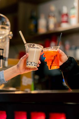 Portakal renkli bir makineyi barın üstünde plastik bardakla paketlemek için yakın plan. Makineyi kullanan bir kız.