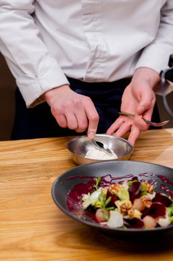 Yanında beyaz sosla süslenmek üzere olan bir kase salata.