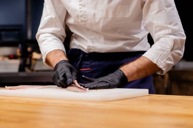 Profesyonel bir mutfakta yemek pişirmeden önce bıçakla balık kesen bir aşçının yakın çekimi.