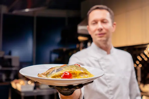 厨师在一个专业的厨房里展示一个有手臂长的现成的鱼肉盘 — 图库照片