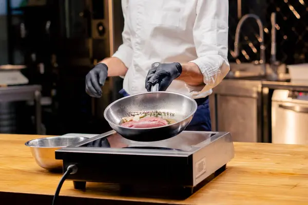 厨师的特写镜头 他们拿着一个煎锅 锅上有一块粉色鸭胸肉 炉子上有迷迭香 — 图库照片