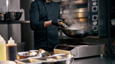 Şef mutfakta elinde bir tavayla fırında yumurta ve etle yemek yemeye hazır bekliyor.