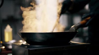 Yakın plan şefi elinde hazır erişteyle bir kızartma tavası tutuyor gün batımının arka planında