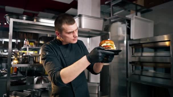 Müessesenin Mutfağındaki Aşçı Elinde Siyah Tabakta Duran Hazır Hamburgeri Inceliyor — Stok video
