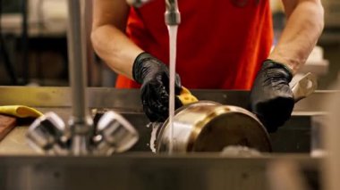 Profesyonel ekipman kullandıktan sonra kirli bulaşıkları yıkayan bir kadının yakın plan fotoğrafı.