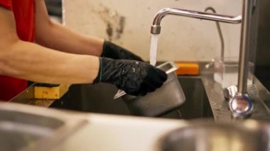 Profesyonel ekipman kullandıktan sonra kirli bulaşıkları yıkayan bir kadının yakın plan fotoğrafı.