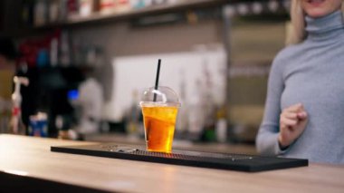 Bir kadının elinin yakın çekimi pipetle hazır portakal kokteyli verir.