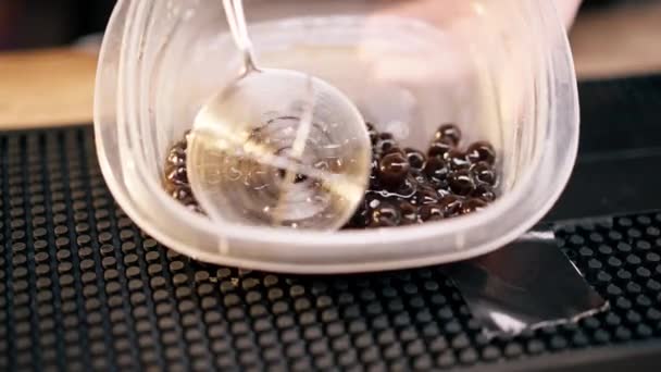 在酒吧柜台后面用一个卡利科勺子把所需数量的黑果冻球挖出来 — 图库视频影像