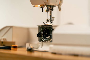 Dikiş atölyesinde yarı monte edilmiş dikiş makası maşası ve iplikleri yakın plan.