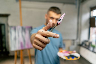 Bir sanat stüdyosunda bir sanatçı palet bıçağıyla ölçümleri doğrudan kameraya alır.