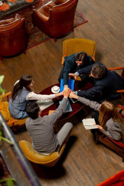 Büyük, güzel bir ofis çalışanının en iyi pozu sandalyelerde oturup ellerini birleştirirken.