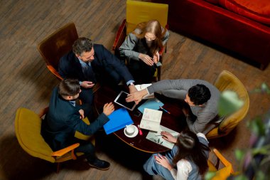 Büyük, güzel bir ofis çalışanının en iyi pozu sandalyelerde oturup ellerini birleştirirken.