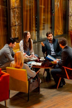 Sarı koltuklarda oturan büyük, güzel bir ofis çalışanının en iyi görüntüsü bir anlaşmayı tartışıyor.