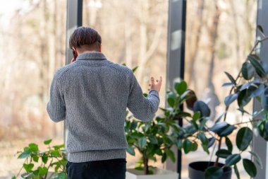 Sakallı genç bir adam. Bir ofis çalışanı pencerenin yanında duruyor ve iş görüşmesi yapıyor.