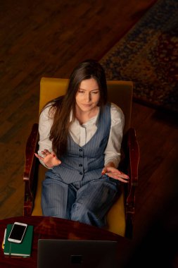 Ofiste, sarı bir sandalyede, ofis çalışanı bir kızın dizüstü bilgisayarla toplantı yapması.