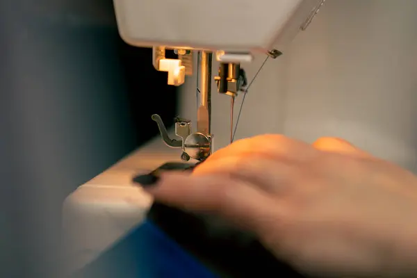 在缝纫机上的一个缝纫车间里 女裁缝在蓝色的面料上做了一个裁剪 — 图库照片