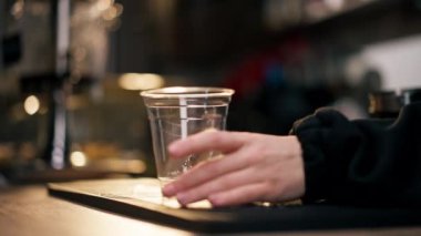 Barın arkasındaki bir müessesede genç bir kız bardaktan plastik bardağa buz dolduruyor.