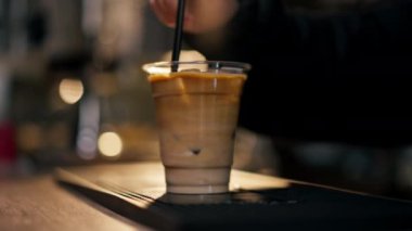 Bar tezgahına yakın plan bir kız pipetle hazır soğuk bir içecek karıştırıyor.