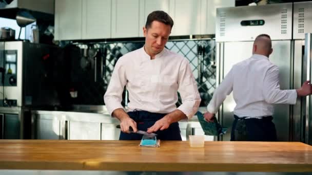 Chef White Jacket Kitchen Table Sharpens Knife Green Stove — Stock Video