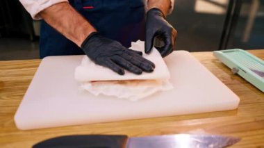 Bir şefin elleri profesyonel bir mutfakta havluyla tahtayı silerken.