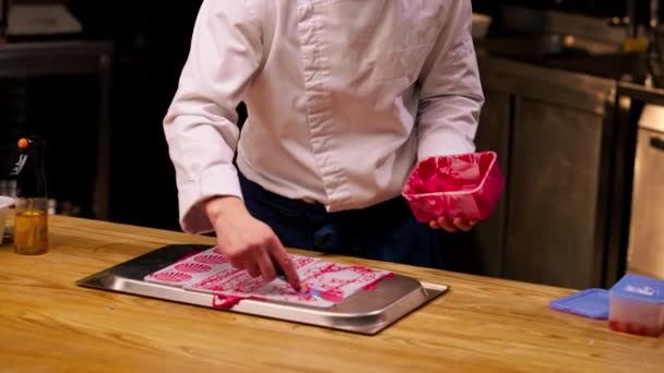 Keittiömestari Seisoo Pöydän Ääressä Levittää Vaaleanpunaista Makeaa Levinneisyyttä Lomakkeelle — kuvapankkivideo