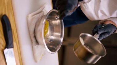 Şefin ellerinin bir tavadan masaya sarısı konmuş bir kaseye döküldüğü dikey bir video.