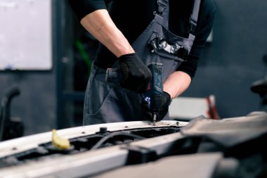 Bir benzin istasyonunun tamircisine yakın çekim yapmak arabanın içindeki cıvataları matkapla sıkılaştırır.