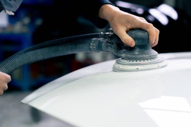 Beyaz bir arabanın bir parçasını cilalarken bir benzin istasyonuna yakın çekim.