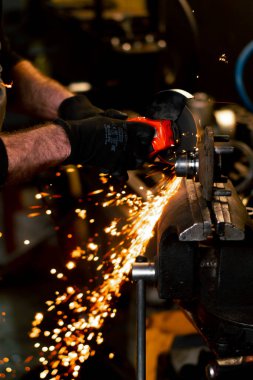 Benzin istasyonunda çalışan bir araba tamircisinin, kıvılcımlar saçan bir açıölçer ile yakın plan fotoğrafı.