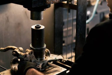 Bir benzin istasyonunda, bir otomobil tamircisinin elleri ve bir arabanın plakası.