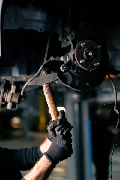 亭子里的加油站里的特写镜头汽车机修工用铁锤在汽车轮圈上的螺栓上 — 图库照片