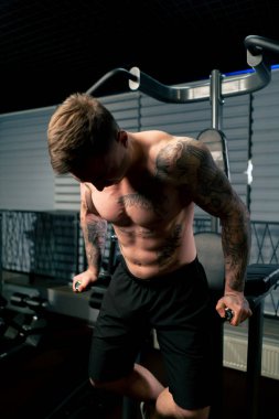 Spor salonunda dövmeli genç yakışıklı adam kendini yukarı çekti ve kollarını yatay çubuğa koydu.