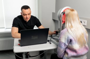 Bir göz hekiminde genç bir doktor genç bir kızın göz bebeklerini teşhis eder.