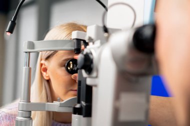 Bir göz hekimliği kliniğine yakın çekim. Kızlar lensi taktılar ve gözünün altına baktılar.