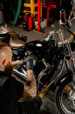 Motosiklet tamircisinde bir tamirci filtreyi çıkarıp yenisiyle değiştiriyor.