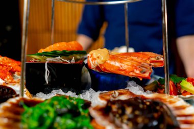 Japon restoranına yakın çekim yapan mavi elbiseli bir şef pahalı bir tabak deniz ürünü hazırlar.