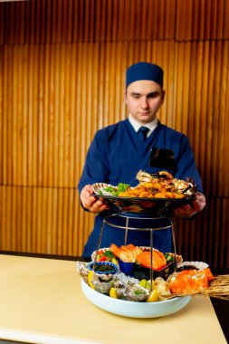 Bir Japon restoranında mavili bir şef pahalı bir deniz ürünü tabağı hazırlar.