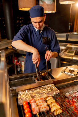 Bir Japon restoranında şef balıklar için meze olarak çeşitli sebzeler pişirir.