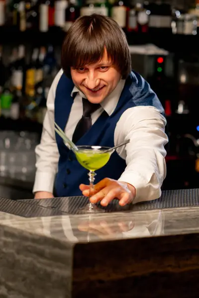 in a Japanese restaurant the bartender stands on the bar counter offering a ready-made cocktail