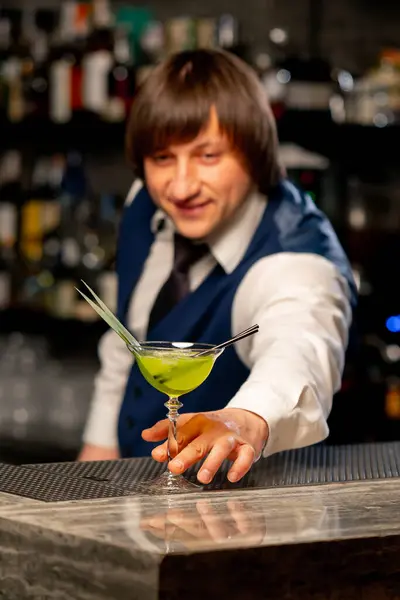 in a Japanese restaurant the bartender stands on the bar counter offering a ready-made cocktail
